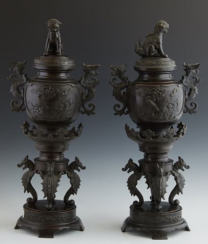 Pair of Japanese Bronze Censers, c. 1900, the lids with Foo lion handles over baluster sides with relief garden scenes with dragon handles, on four dr