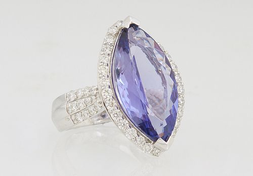 Lady's Platinum Dinner Ring, with an 8.22 carat marquise tanzanite atop a conforming border of round diamonds, the tapered shoulders of the band with 