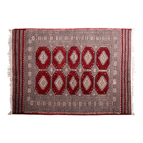 Tapete. Siglo XX. Estilo Bokhara. Elaborado en fibras de lana y algodón. Decorado con motivos geométricos sobre fondo vino.