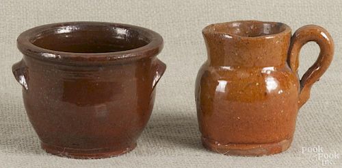 Two pieces of miniature Pennsylvania redware, 19th c., to include a creamer, 3'' h., and a crock