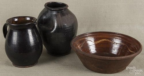 Three pieces of Pennsylvania redware, 19th c., to include a pitcher, 8'' h., a crock, 9 1/2'' h.