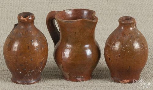 Three pieces of miniature Pennsylvania redware, 19th c., to include two jugs, 3 3/8'' h.