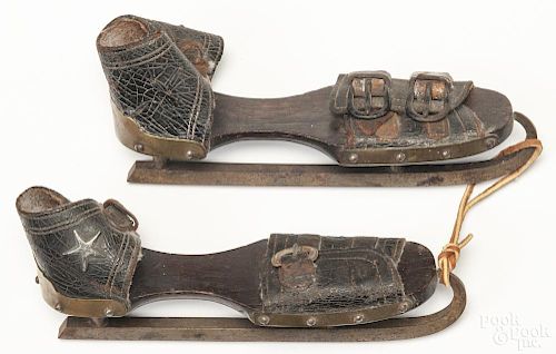 Pair of walnut, leather, and brass ice skates, 19th c., with applied stars, 9 1/4'' l.