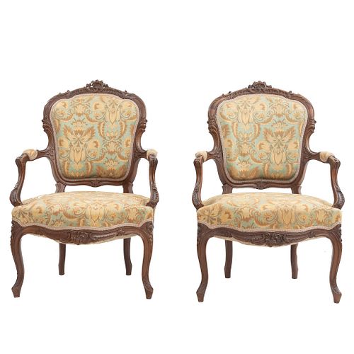 Par de sillones. Francia. Siglo XX. En talla de madera de nogal. Con respaldos y asiento en tapicería floral.