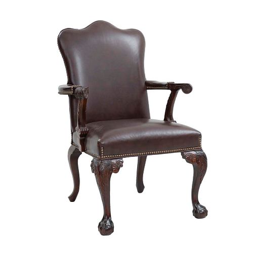 Sillón. Siglo XX. Estilo inglés. En talla de madera. Con respaldo cerrado y asiento de piel color marrón.