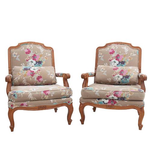 Par de sillones. Siglo XX. En talla de madera. Con respaldos cerrados y asientos con cojínes en tapicería floral color beige.