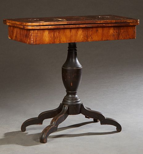 American Classical Carved Walnut Games Table, 19th c., the swiveling top over open storage, on a baluster urn form support, to a qua...