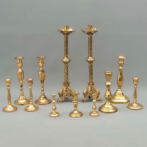 Lote de 12 candeleros. Siglo XX. Diferentes diseños. Elaborados en metal dorado. Con arandelas circulares y florales.