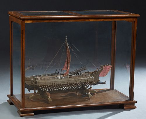 Hand Carved Wooden Ship's Model of a Roman Bireme, from the 1st century, 20th c., presented in a custom glazed oak display cabinet on block feet, H.- 