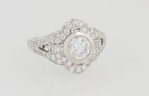 Lady's Platinum Dinner Ring, with a central .99 ct. round diamond, atop a shaped top with round diamonds, the diamond mounted split shoulders of the b