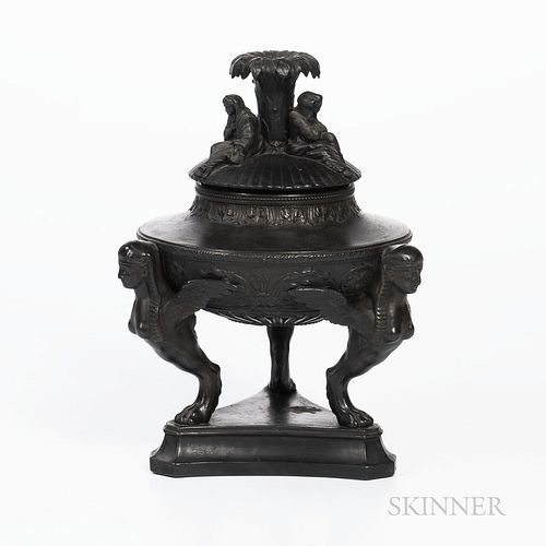 Wedgwood Black Basalt Tripod Urn and Cover, England, 19th century, fluted cover with three seated Sybil figures surrounding a central r