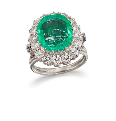 AN EMERALD AND DIAMOND CLUSTER RING
 Centred by a claw-set 