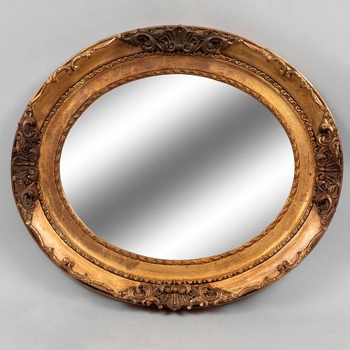 Espejo. Siglo XX. Diseño oval. Elaborado en madera estucada y dorada. Con luna oval biselada. 60 x 67 cm