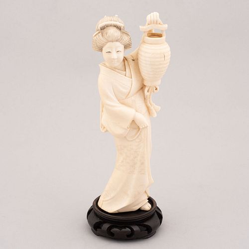 Geisha con lámpara. China. Siglo XX. En talla de marfil. Con base de madera tallada. Decorada con elementos esgrafiados en tinta negra.