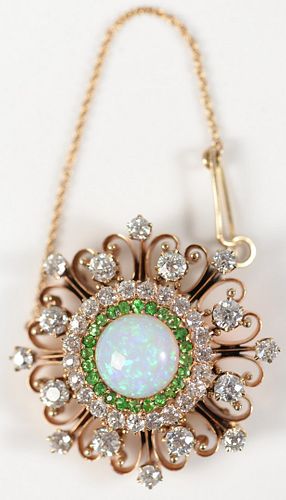 14 Karat Gold Brooch/Pendant
with center fire opal, encircled by green garnets, surrounded by rows of diamonds
diameter approximately 4 carats total w