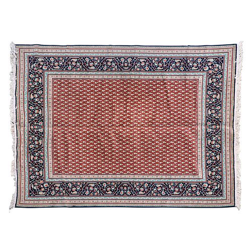 Tapete. Siglo XX. En fibras de lana. Decorado con motivos orgánicos y florales sobre fondo rojo con cenefa azul.