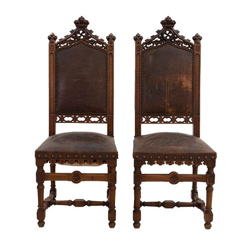 Par de sillas. Francia. Siglo XX. Estilo Enrique II. En talla de madera de nogal. Con respaldos semiabiertos.