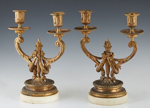 Pair of Gilt Bronze Louis XVI Style Two Light Candelabra, early 20th c., the central torch flanked by curved candle arms, to a stepped base on a marbl