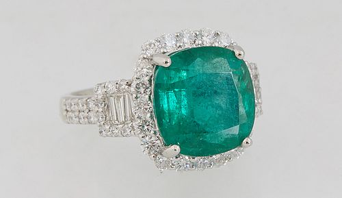 Lady's Platinum Dinner Ring, with a 6.59 carat cushion cut emerald atop a border of round diamonds, flanked by baguette and round diamond lugs over di