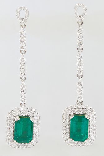 Pair of 18K White Gold Pendant Earrings, the pear shaped diamond mounted stud over a 9 round diamond chain to a pendant 3.28 carat emerald atop a conc