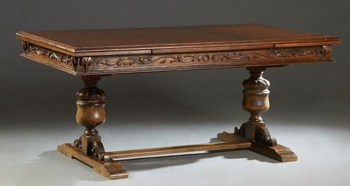 Spanish Renaissance Style Carved Oak Draw Leaf Dining Table, early 20th c., the rounded edge top over a carved skirt and two draw leaves, on run form 