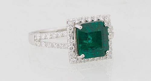Lady's 18K White Gold Dinner Ring, with a square 2.69 carat emerald atop a triple concentric graduated diamond border, the split shoulders of the band