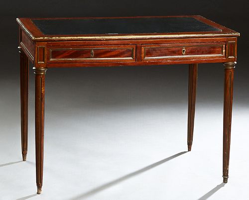 French Louis XVI Style Carved Mahogany Ormolu Mounted Writing Table, early 20th c., the inset leather top with an ormolu banding over two frieze drawe
