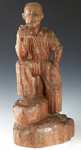 American Folk Art Carved Wooden Figure, 19th c., of a seated Afro-American man smoking a pipe, carved from a single log, H.- 22 in., W.- 10 1/2 in., D
