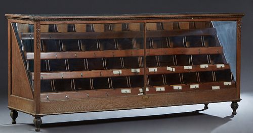 Large Oak Candy Case, c. 1910, with four rows of removable sliding drawers, with glass tops, fronts and triangular sides, on a plinth base on turned l