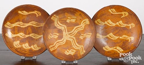 Three slip decorated redware plates, 19th c.