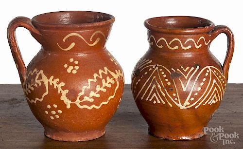 Two Mexican slip decorated redware pitchers, 19th c., 6 3/4'' h. and 6 1/4'' h.