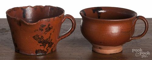 Two Pennsylvania redware handled cups, 19th c., with manganese splotching, one with a spout, 3'' h.