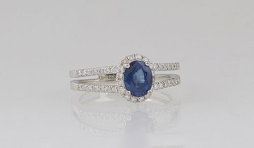 Lady's Platinum Dinner Ring, with an oval 1.05 ct. blue sapphire atop a border of tiny round diamonds, the split shoulders of the band also mounted wi