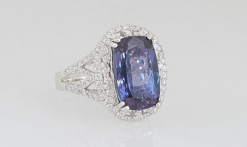 Lady's Platinum Dinner Ring, with a 7.68 ct. oval tanzanite, atop a pierced border of small round diamonds, over pierced diamond mounted shoulders of 