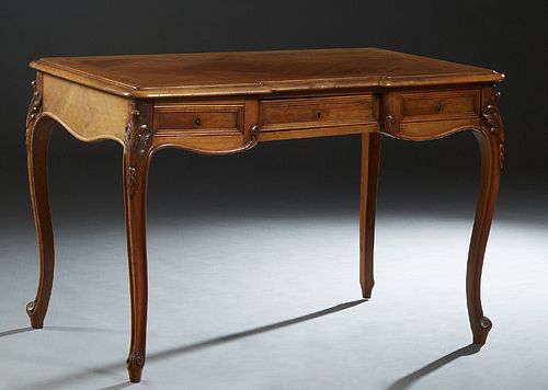 French Louis XV Style Carved Inlaid Walnut Desk, late 19th c., the breakfront stepped sloping edge top over a setback center drawer, flanked by two dr
