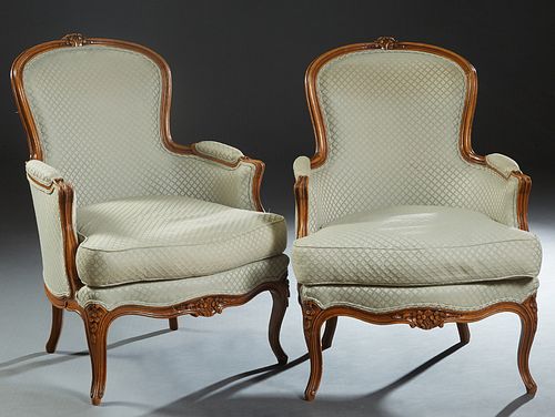 Pair of French Carved Beech Louis XV Style Bergeres, 20th c., the arched curved back with a floral carved crest rail to upholstered arms and and a loo
