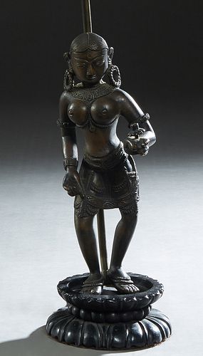 Indonesian Patinated Bronze Female Goddess Figure, early 20th c., the standing figure with a flower in her left hand, now mounted on a circular carved