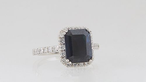 Lady's Platinum Dinner Ring, with a 4.31 ct. cushion cut blue sapphire atop an octagonal border of small round diamonds, the shoulders of the band als