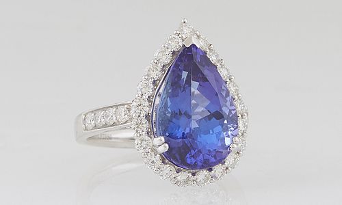 Lady's Platinum Dinner Ring, with an 8.74 ct. pear shaped tanzanite atop a conforming border of round diamonds, the shoulders of the band with graduat