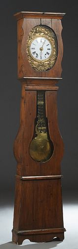 French Provincial Carved Pine Tallcase Clock, 19th c., the stepped crown over a brass repousse face with scroll and floral decoration, around an ename