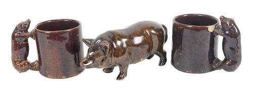 Three Brown Glazed Pottery Pieces, to include standing pig, height 4 inches; along with a pair of mugs with pig form handles, height 3 inches. Provena