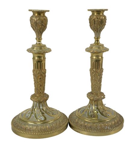 Pair of Louis XVI Style Gilt Candlesticks, foliate cast stem on round foot, with beaded border, height 11 inches. The Estate of Gloria Schiff, 630 Par