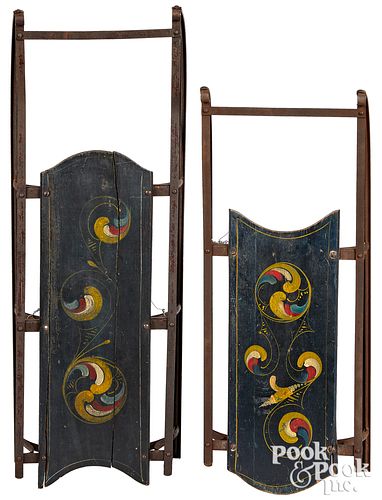 Two similar painted sleds, with swirl decoration
