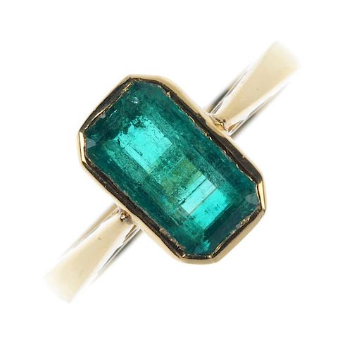 An 18ct gold emerald single-stone ring. The rectangular-shape emerald collet, to the tapered shoulde