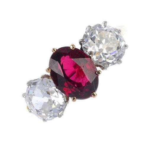 A diamond and ruby three-stone ring. The oval-shape ruby, with old-cut diamond sides, to the plain b