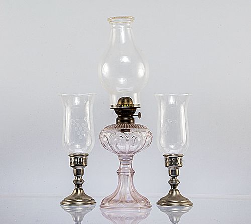 Lote de 3 piezas. Siglo XX. Elaborados en pewter y vidrio prensado con aplicaciones de metal. Consta de: Quinqué y par de candeleros.