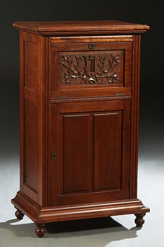 American Carved Mahogany Music Cabinet, late 19th c., the stepped rounded edge top over a fall front enclosing two shelves, above a lower cabinet door