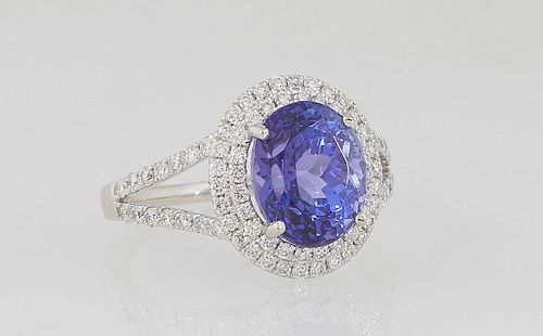 Lady's Platinum Dinner Ring, with an oval 4.05 tanzanite atop a conforming double graduated border of round diamonds, the split shoulders of the band 