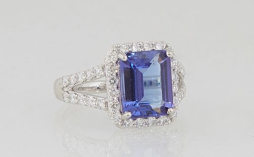 Lady's Platinum Dinner Ring, with an emerald cut 3.64 carat tanzanite atop an octagonal border of small round diamonds, the split shoulders of the ban