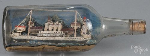 Folk art painted model ship and village in a bottle, likely the RMS Olympic, early 20th c.